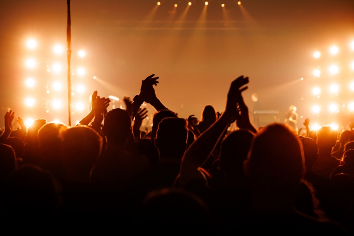 Silhouetted crowd clapping hands at live music concert stage background